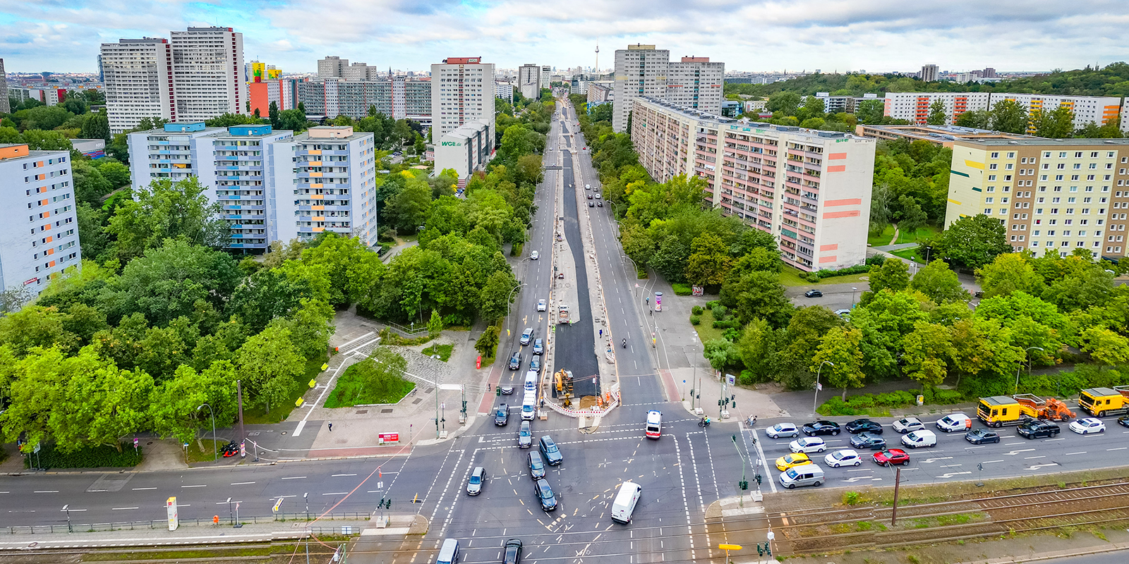 Kreuzung einer großen Verkehrsstraße mit Hochhäusern im Hintergrund