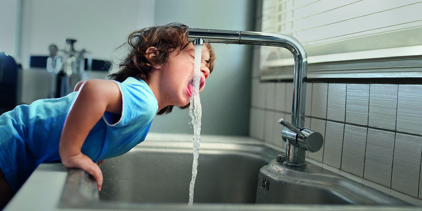 Kind trinkt Leitungswasser am Wasserhahn