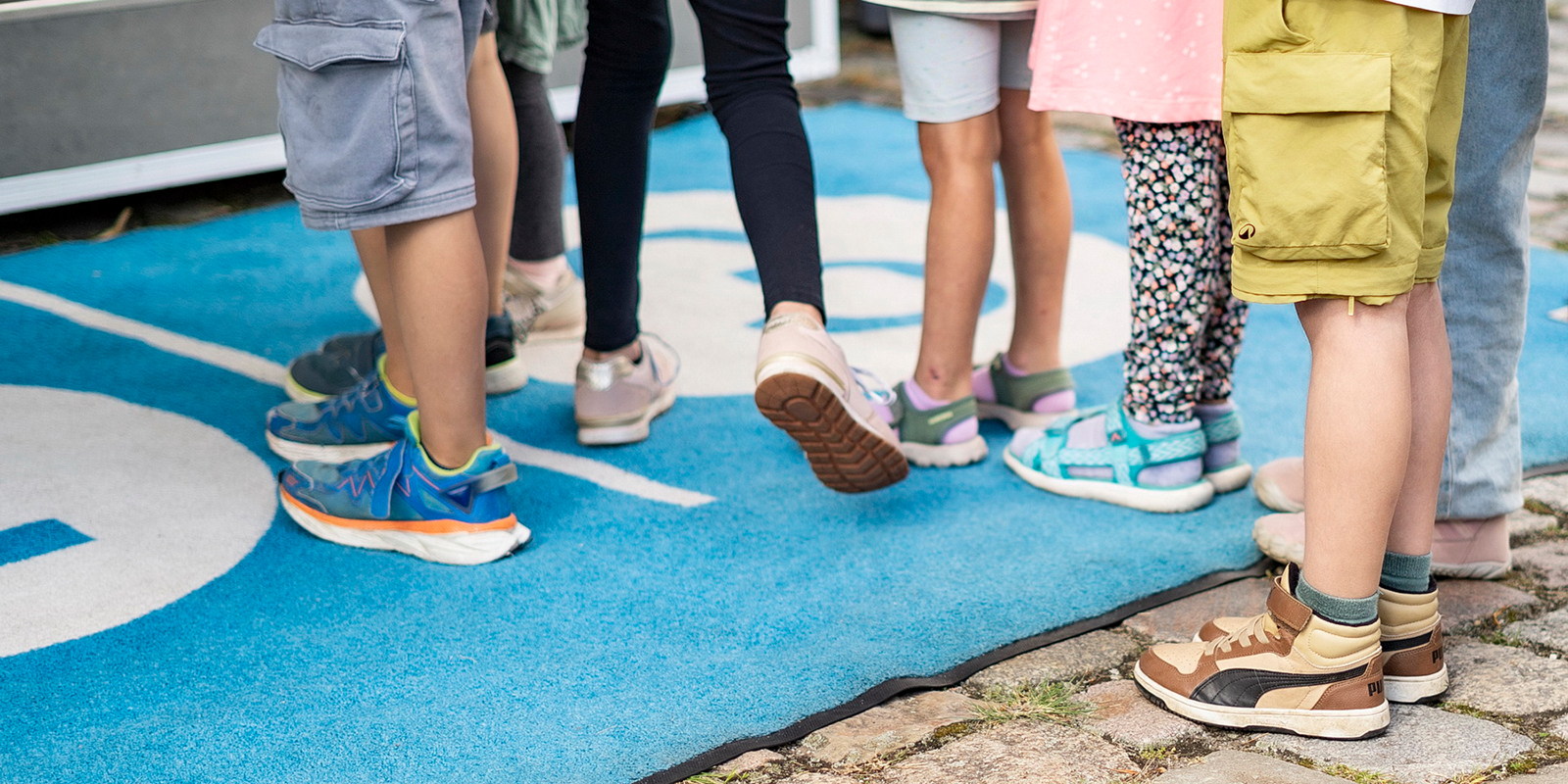 Schülerinnen und Schüler spielen das Wasser-Quiz, zu sehen sind nur die Beine und Füße der Kinder