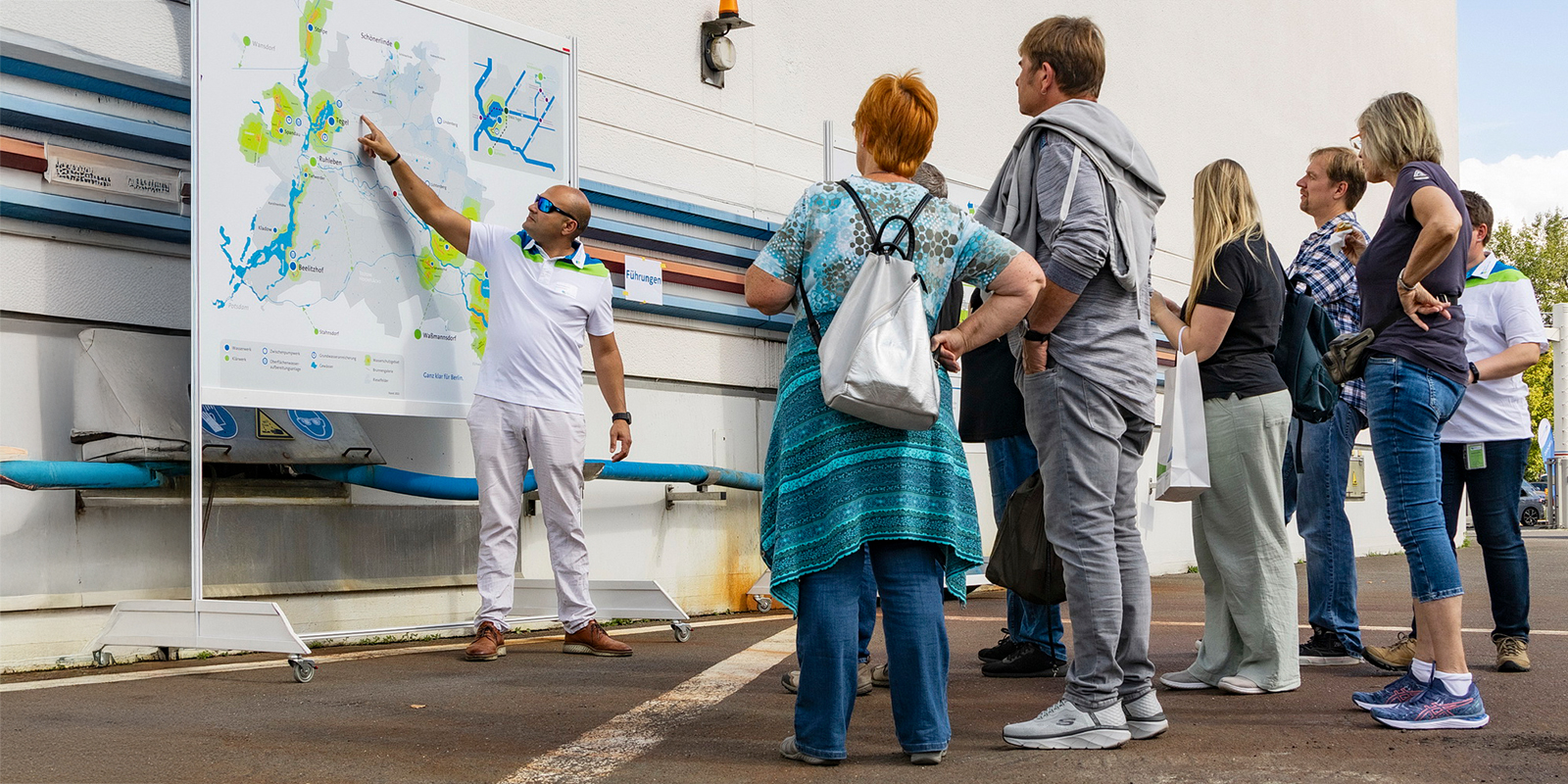 Eine Gruppe Menschen bekommt anhand eines Lageplans von bei einer Werksführung etwas erklärt