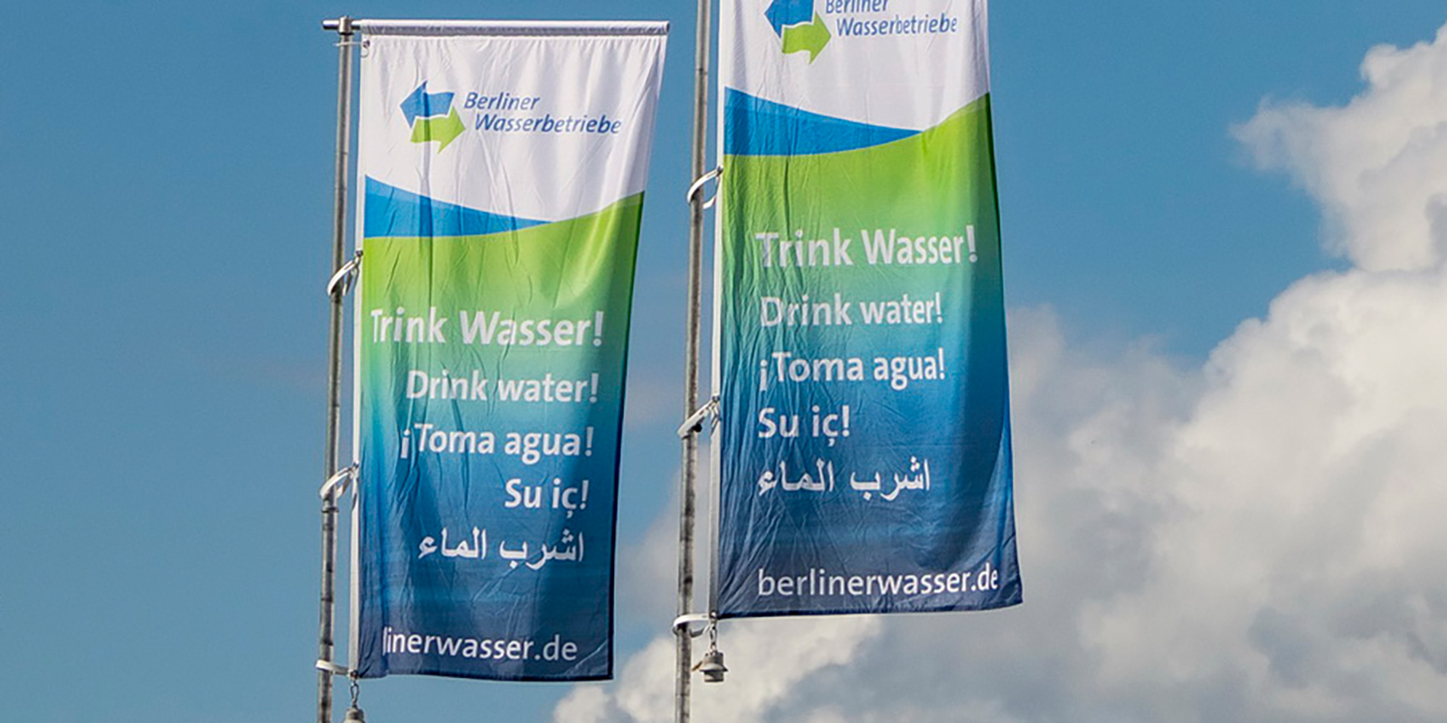 Zwei Fahnen der Berliner Wasserbetriebe flattern im Wind