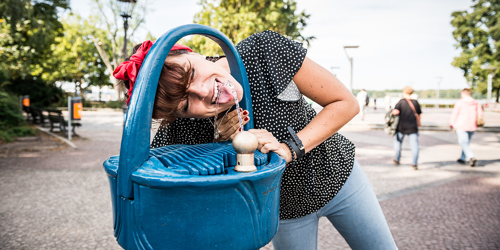 Frau trinkt am Trinkbrunnen
