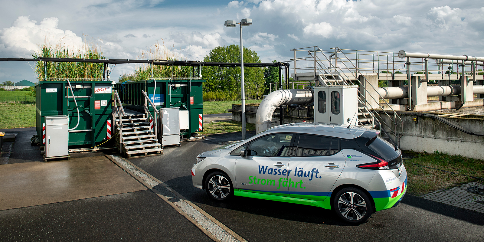 Ein e-Fahrzeug steht vor ein paar Schuttcontainern auf dem Klärwerksgelände