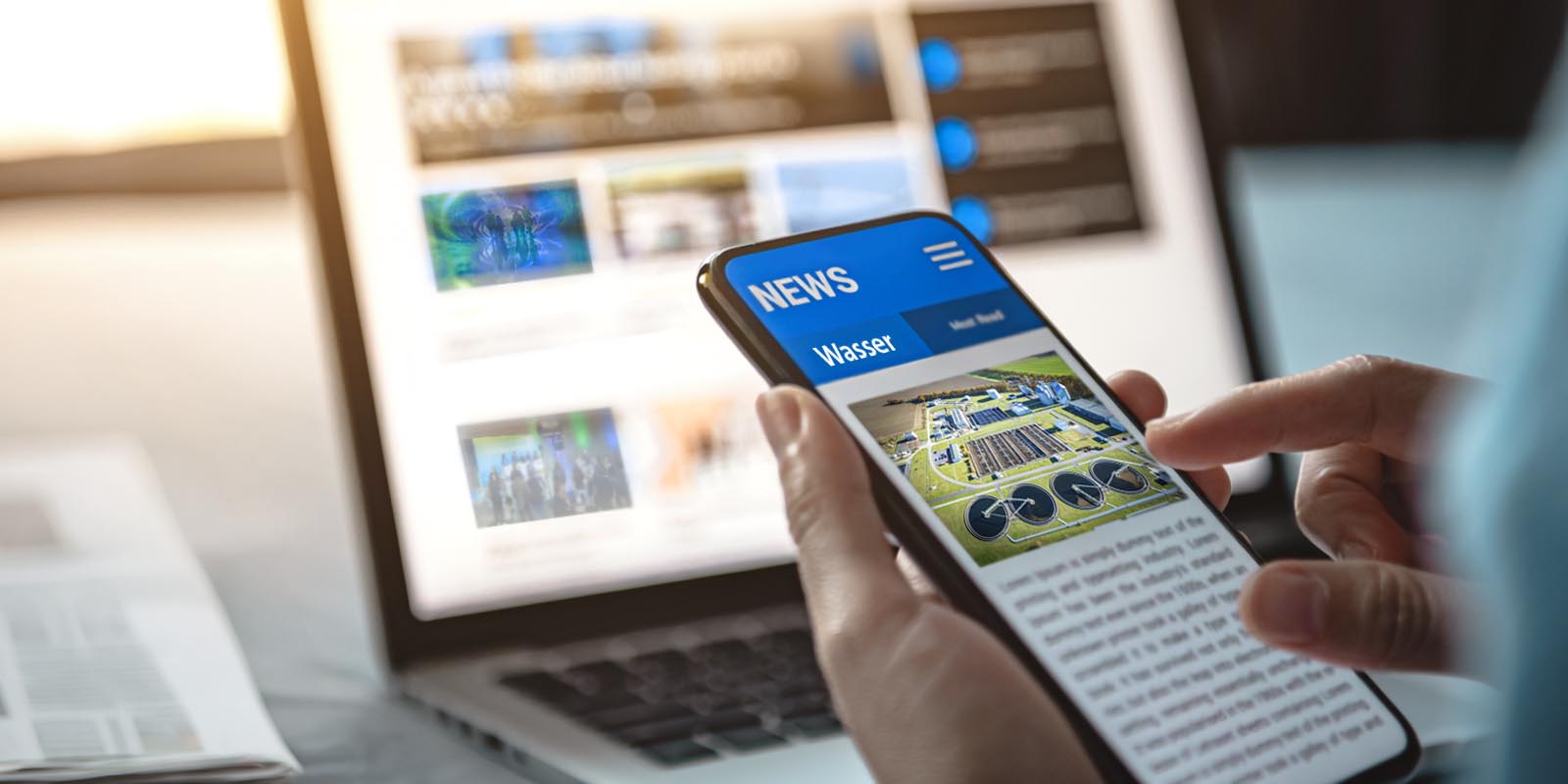 Hand hält Mobiltelefon auf dem eine Newsseite abgebildet ist