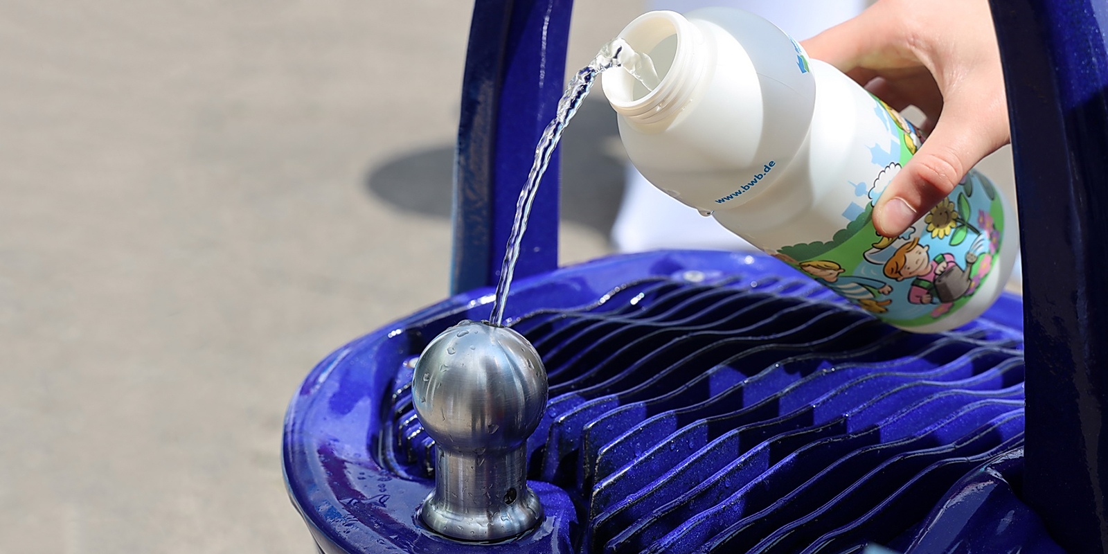 Kind füllt Flasche am Trinkbrunnen