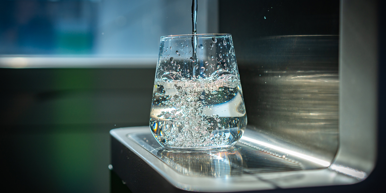Frau zapft Wasser an einem Wasserspender
