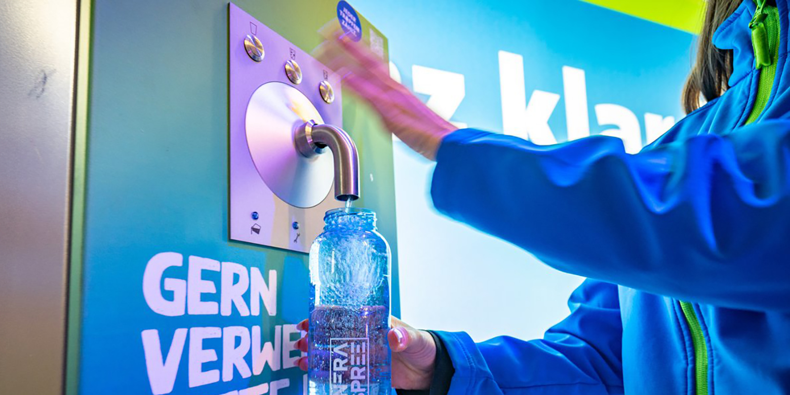 Frau zapft Wasser an einem Wasserspender