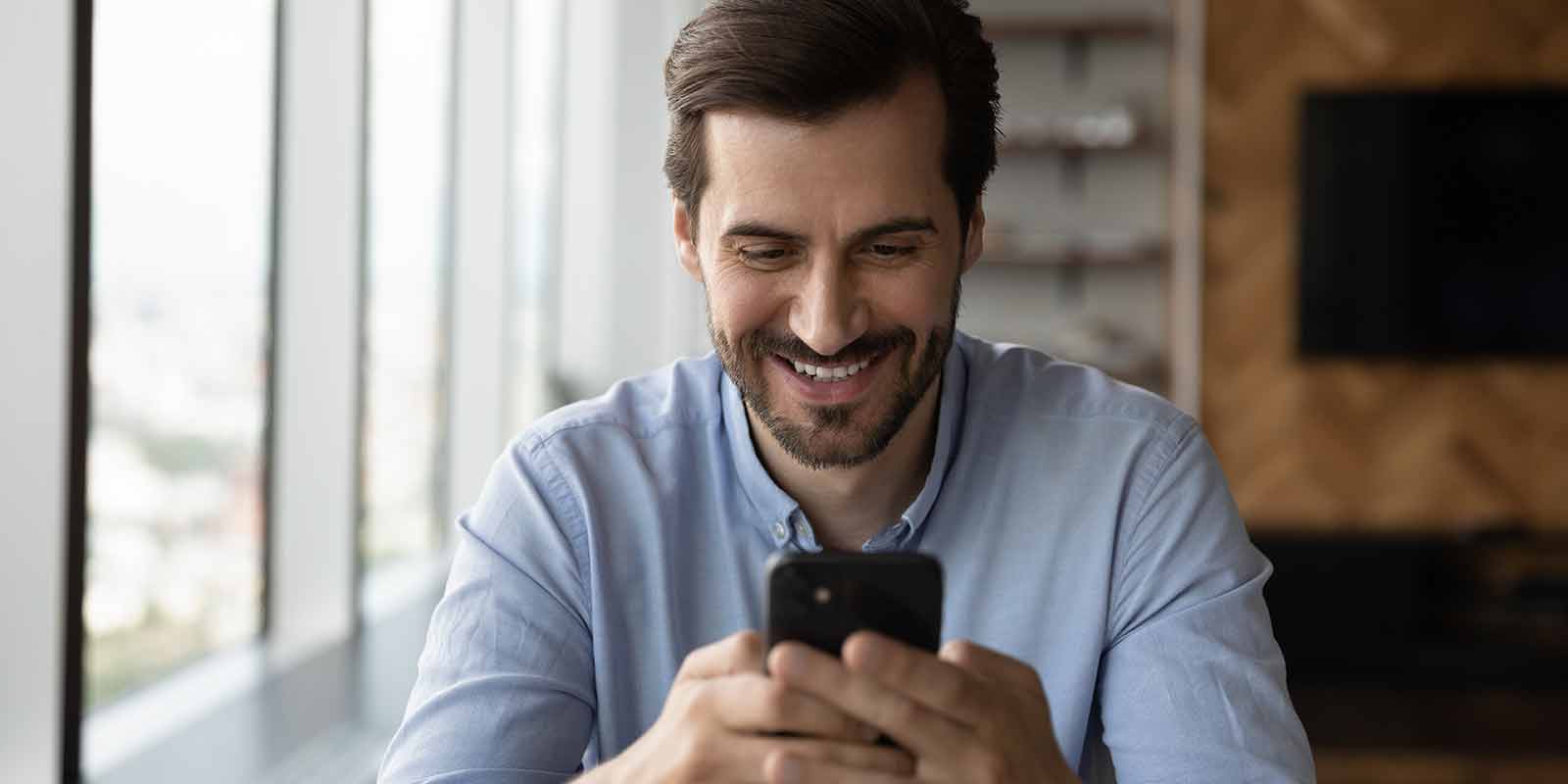 Ein Mann schaut auf ein Mobiltelefon