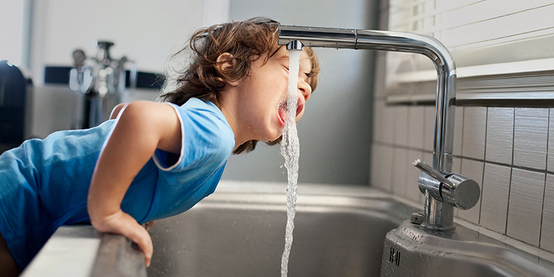 Junge trinkt vom Wasserhahn