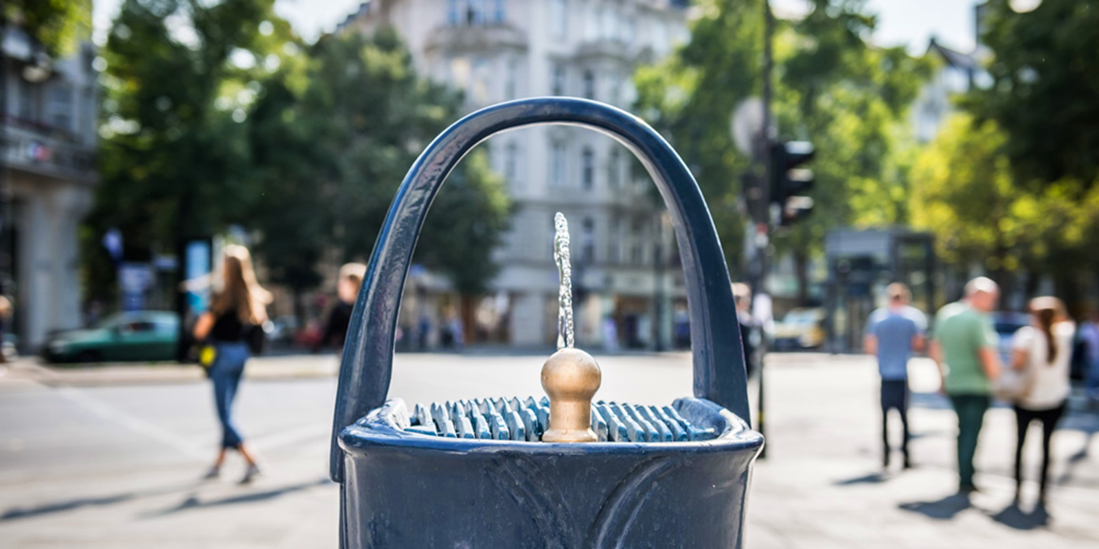 Zwei Personen erfrischen sich an einem Trinkbrunnen