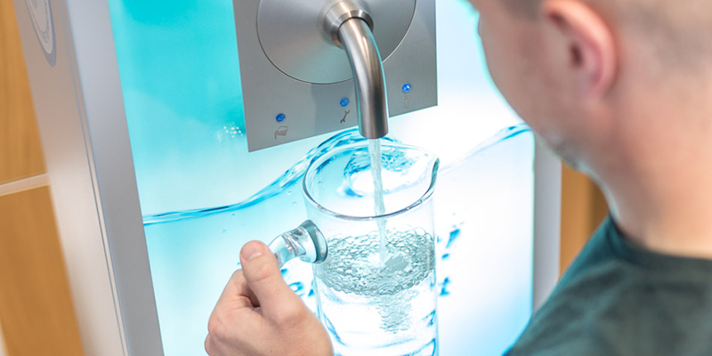 Mann zapft Wasser an einem Wasserspender 