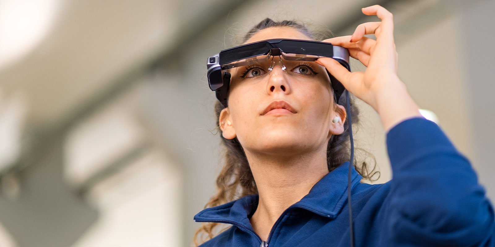 Junge Auszubildende schaut durch eine Computerbrille