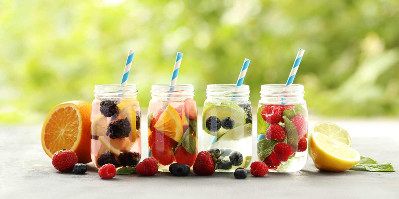 Vier Gläser mit Früchten und Wasser