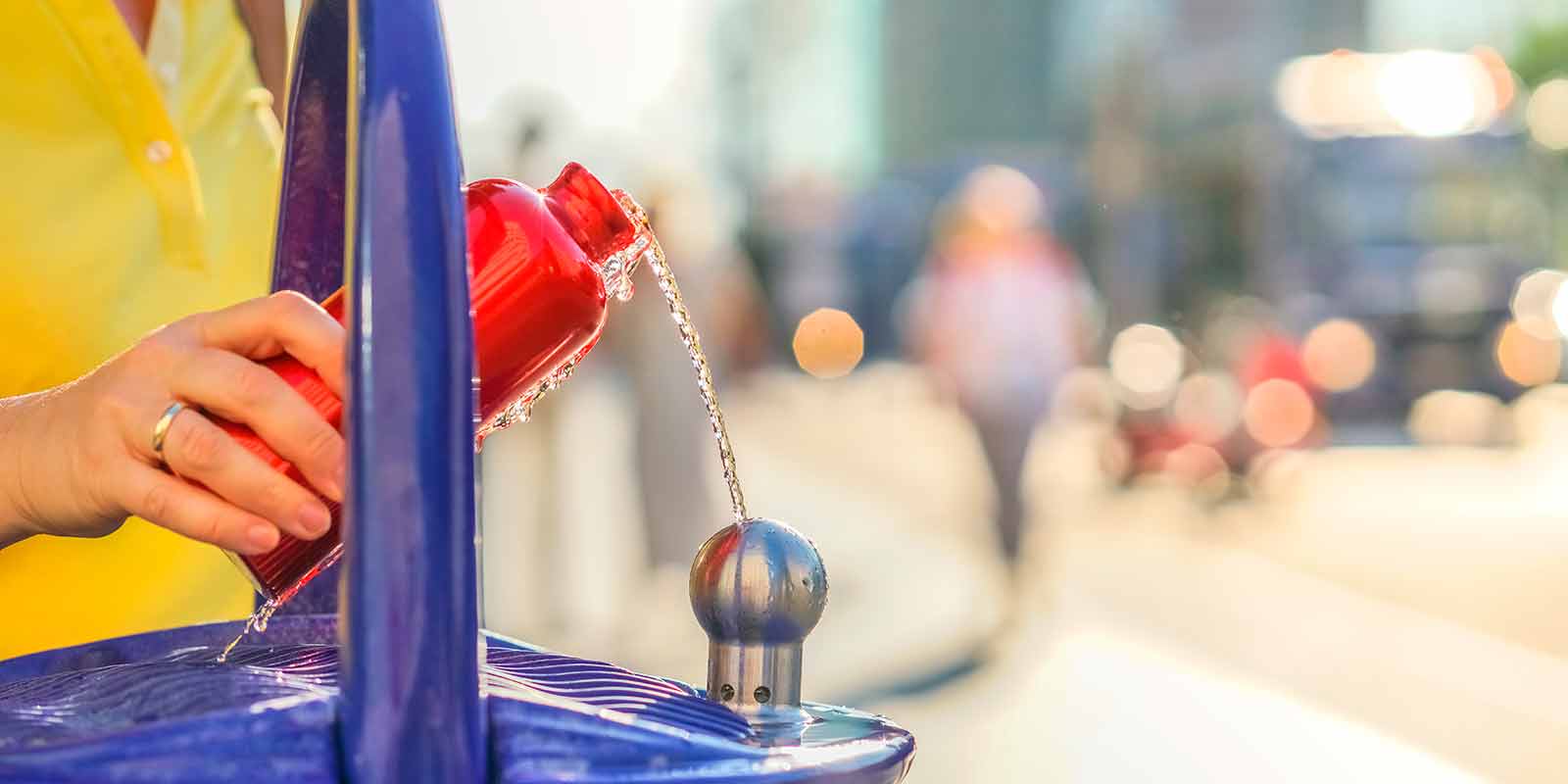 Eine Trinkfalsche wird an einem Berliner Trinkbrunnen mit Wasser befüllt.