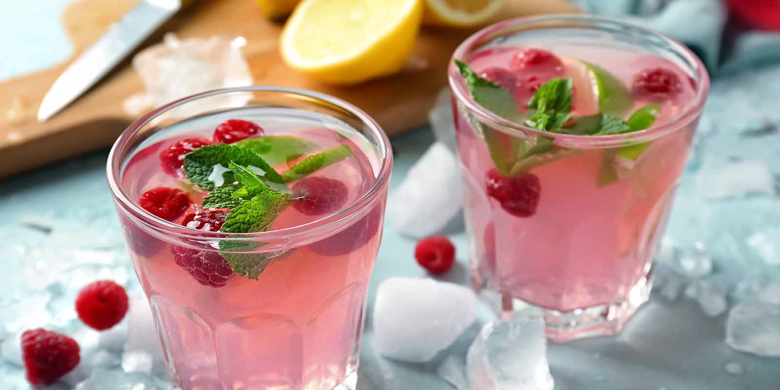 Zwei Gläser, die mit Wasser gefüllt sind und Beeren und Minze ethalten.