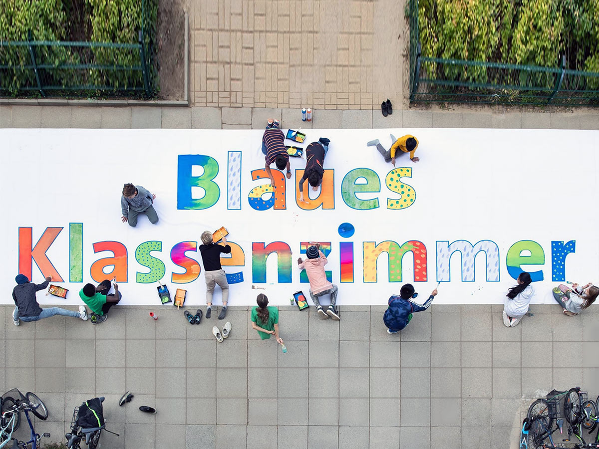 Kinder malen den Schriftzug "Blaues Klassenzimmer" auf einem Banner aus